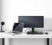 Side-by-side image of a laptop and a desktop computer on a modern desk setup, highlighting size and design differences.